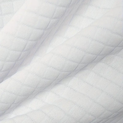 Weiße, gesteppte Stoffstruktur, Nahaufnahme. Weicher, texturierter Baumwollstoff, ideal für Bettwäsche oder Kleidung. Hochwertiges Material.