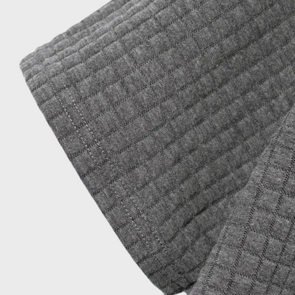 Graues, gestepptes Textil mit quadratischem Muster, Nahaufnahme. Hochwertiger Stoff, ideal für Heimtextilien und Bekleidung.