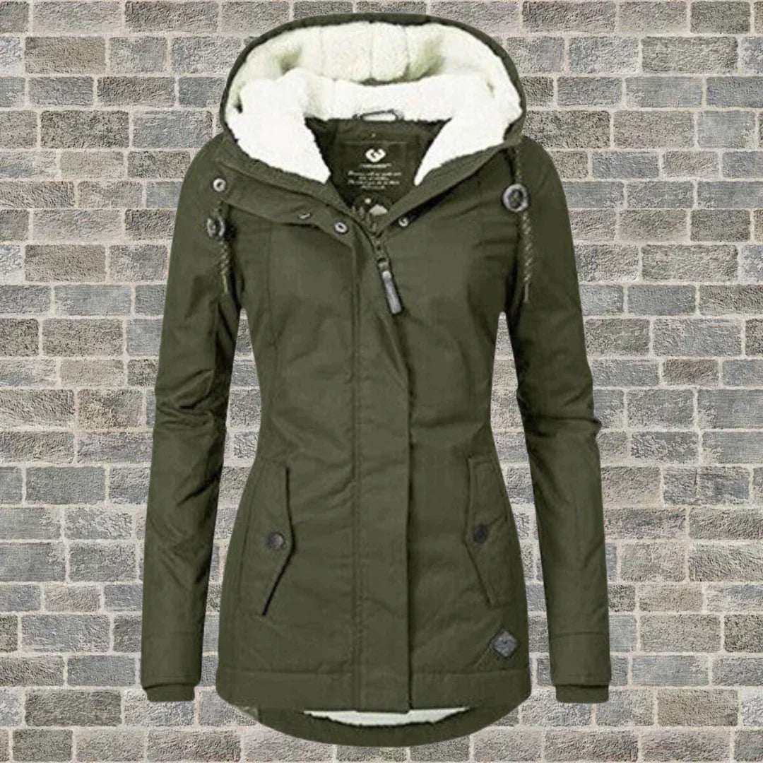 Damen Winterjacke mit Kapuze, olivgrün, gefüttert, vor Ziegelwand. Modische warme Outdoorjacke, ideal für kalte Temperaturen.