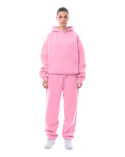 Frau in rosa Hoodie und Jogginghose, lässige Mode, Streetwear, bequeme Kleidung, sportlicher Look, weiße Sneaker, isolierter Hintergrund.