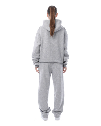 Frau in grauem Jogginganzug von hinten, Kapuzenpullover und Jogginghose, lässige Sportbekleidung, Freizeitmode, bequeme Kleidung.