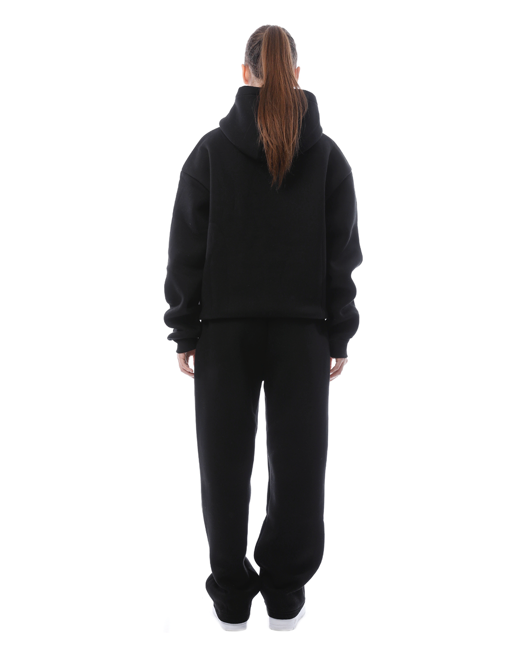 Frau in schwarzem Hoodie und Jogginghose, Rückansicht. Bequeme Freizeitkleidung, sportlicher Look, Mode für Damen, lässiger Stil.