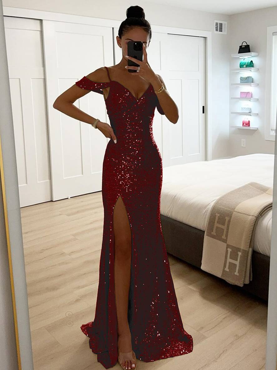 Frau in rotem, schulterfreiem Paillettenkleid mit hohem Schlitz, steht vor einem Spiegel in modernem Schlafzimmer. Elegantes Abendmode-Outfit.