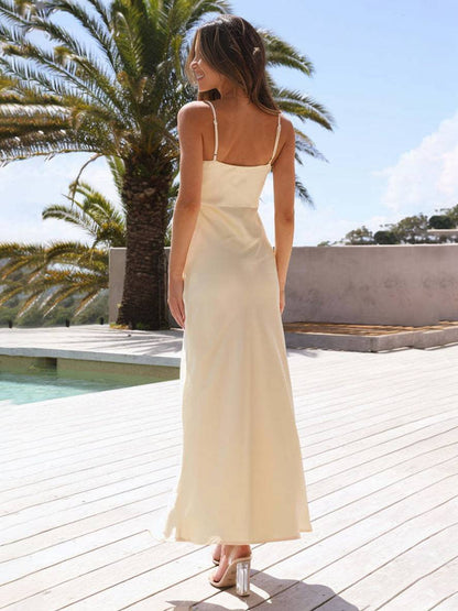 Frau in eleganten, cremefarbenen Sommerkleid auf Holzterrasse, umgeben von Palmen und blauem Himmel. Perfekt für Strandhochzeiten und Sommermode.