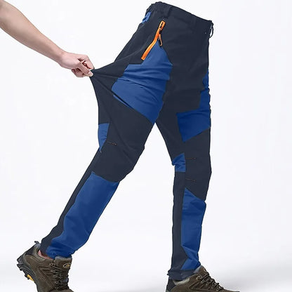Outdoor-Hose in Blau und Schwarz, elastisch, mit orangefarbenem Reißverschluss, ideal für Wandern und Trekking, getragen mit robusten Wanderschuhen.