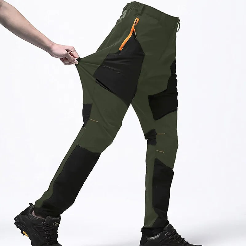 Grüne Outdoor-Hose mit schwarzen Einsätzen, elastischem Bund und Reißverschlusstasche, ideal für Wandern und Trekking.