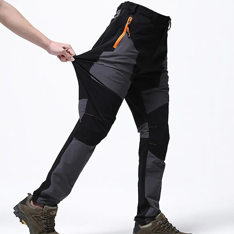 Schwarze und graue Outdoor-Hose mit elastischem Bund und orangefarbenem Reißverschluss, getragen von Person, zeigt Flexibilität und Komfort.