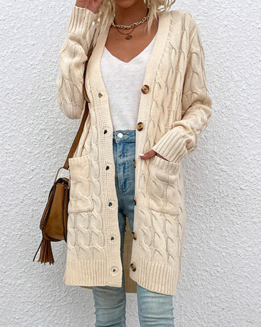 Dame in cremefarbenem Strick-Cardigan mit Zopfmuster, weißem T-Shirt und blauer Jeans vor weißer Wand. Modetrend, Herbstmode, Strickjacke.