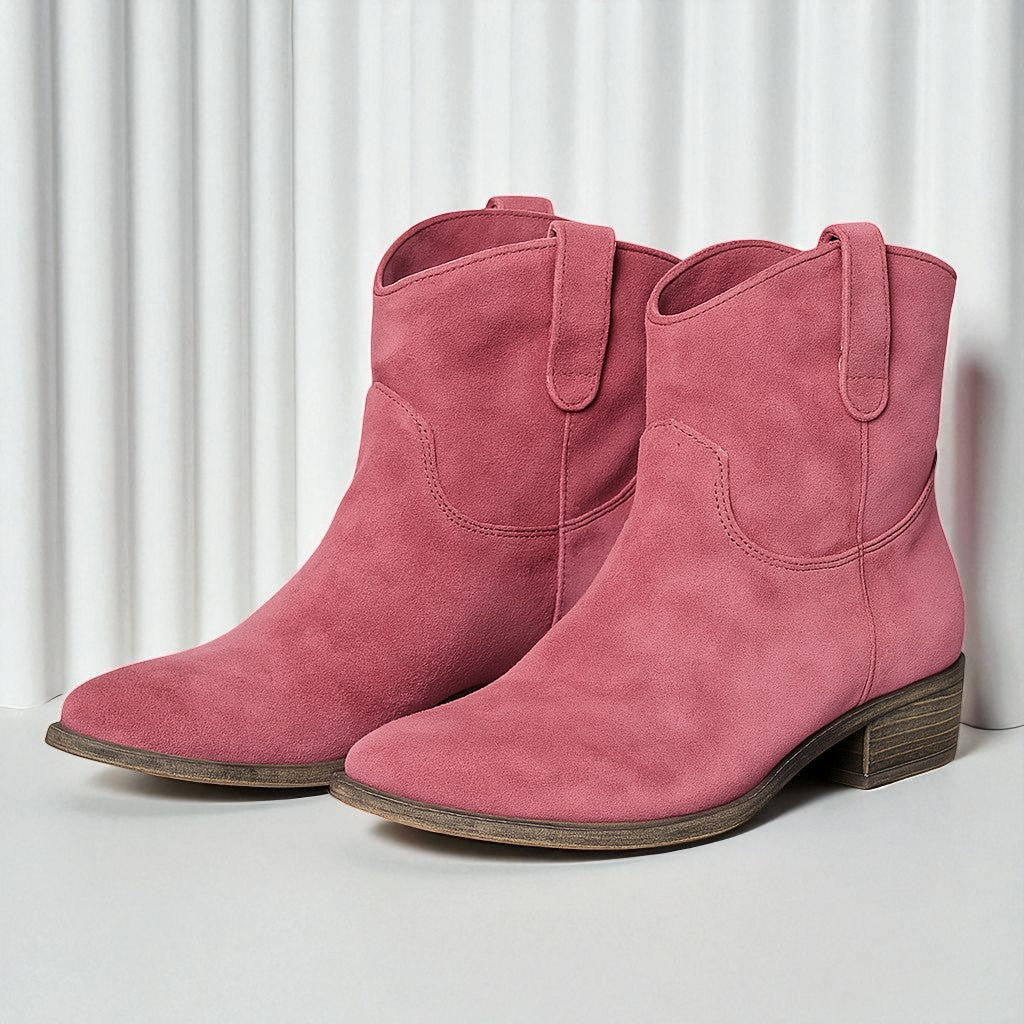 Rosa Wildleder-Stiefeletten mit niedrigem Absatz vor weißem Hintergrund. Modische Damenstiefel, ideal für Herbstmode und trendige Outfits.