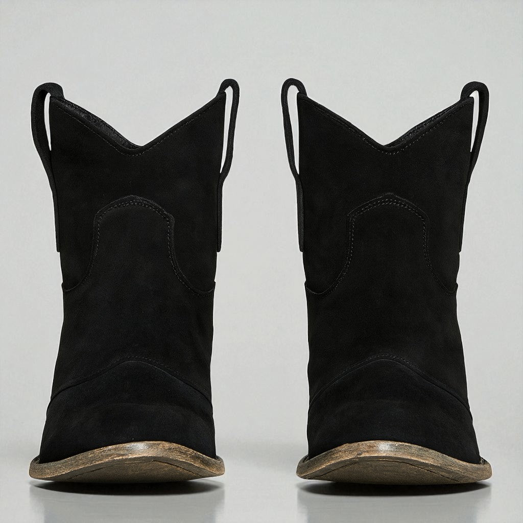Schwarze Cowboy-Stiefel aus Wildleder mit abgenutzter Sohle, frontal fotografiert. Western-Mode, robuste Stiefel, trendige Schuhe.