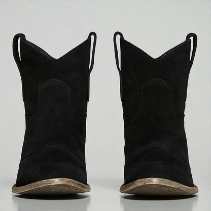 Schwarze Cowboy-Stiefel aus Wildleder mit abgenutzter Sohle, frontal fotografiert. Western-Mode, robuste Stiefel, trendige Schuhe.