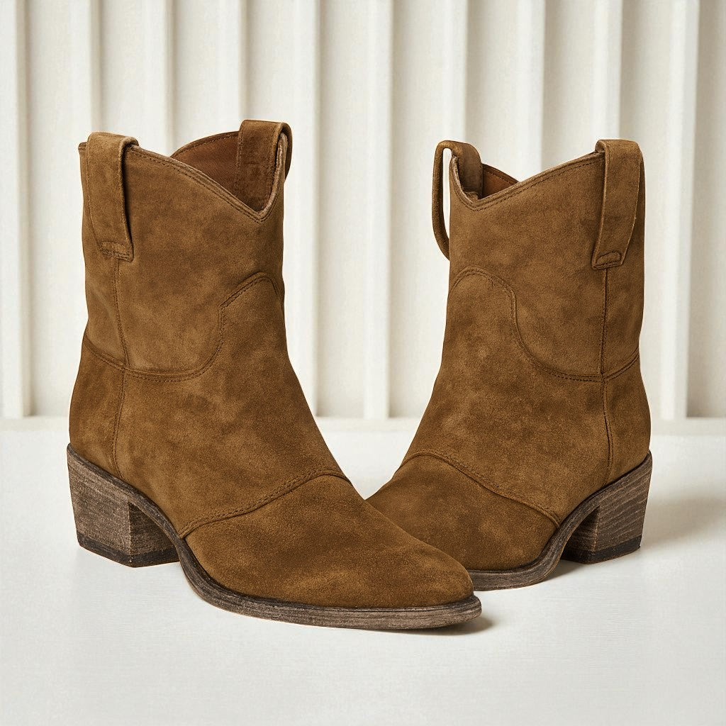 Braune Wildleder-Cowboystiefel mit Blockabsatz vor weißem Hintergrund. Modische Westernstiefel für Damen, ideal für Herbst und Winter.