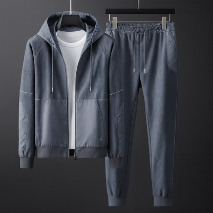 Grauer Herren-Trainingsanzug mit Kapuzenjacke und Jogginghose, aus atmungsaktivem Material, ideal für Sport und Freizeit.