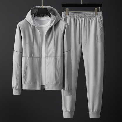 Grauer Trainingsanzug mit Kapuzenjacke und Jogginghose, aus atmungsaktivem Material, ideal für Sport und Freizeit. Perfekt für Herrenmode.