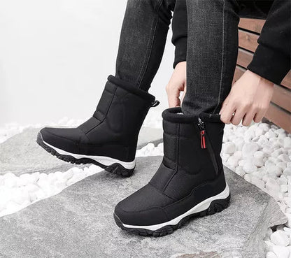 Schwarze Winterstiefel mit Reißverschluss, getragen von einer Person in Jeans, auf grauem Steinboden. Bequeme, warme Schuhe für kaltes Wetter.