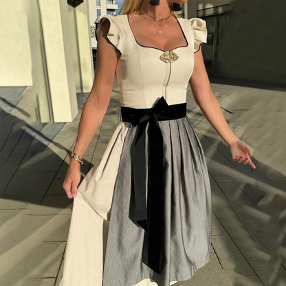 Frau in traditionellem Dirndl mit schwarzem Samtgürtel und Rüschenärmeln, steht im Sonnenlicht. Perfekt für Oktoberfest, Trachtenmode, bayerische Kleidung.