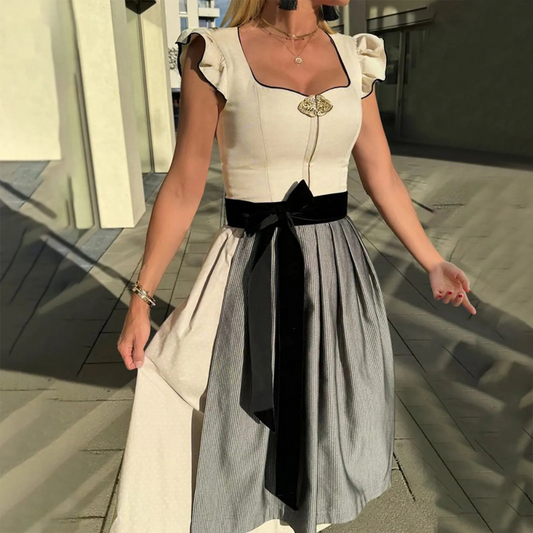 Frau in traditionellem Dirndl mit schwarzem Samtgürtel und Rüschenärmeln, steht im Sonnenlicht. Perfekt für Oktoberfest, Trachtenmode, bayerische Kleidung.