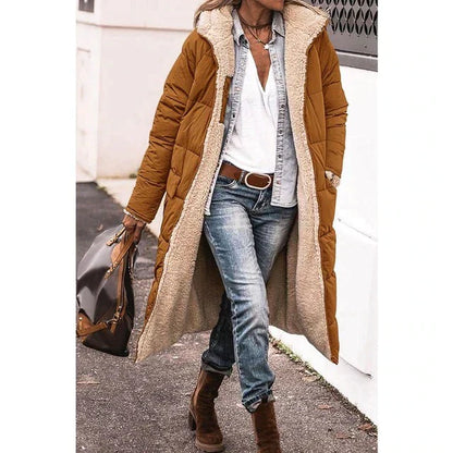 Frau in braunem Daunenmantel mit Fellfutter, Jeans und Stiefeln, trägt braune Tasche. Modischer Winterlook, lässig und stilvoll.
