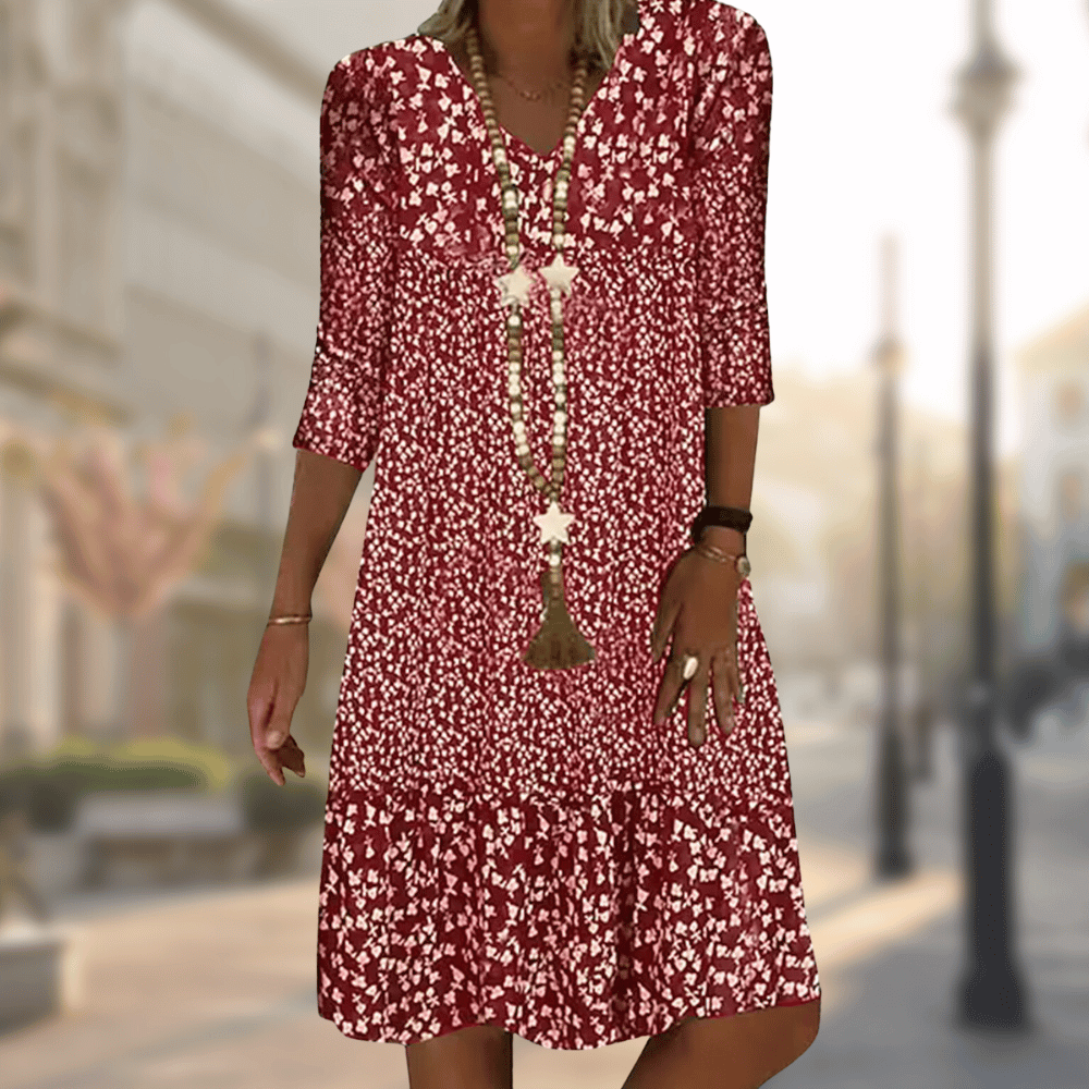 Rotes geblümtes Sommerkleid mit Dreiviertelärmeln, getragen von einer Frau auf einer städtischen Straße. Perfekt für lässige Mode und Sommeroutfits.