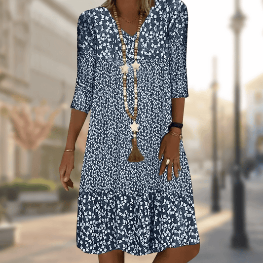 Dame in geblümtem Sommerkleid auf städtischer Straße, blau-weißes Muster, modisches Outfit, lässiger Stil, ideal für warme Tage.