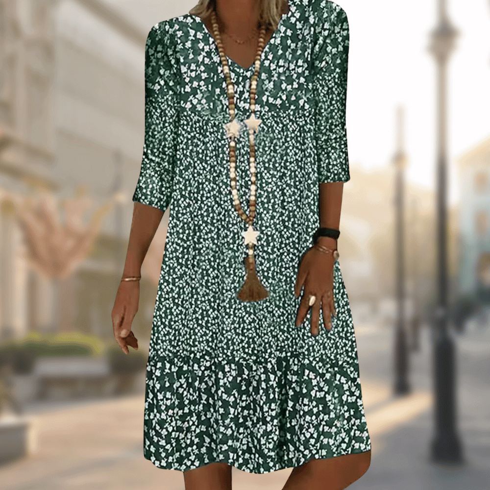 Grünes Sommerkleid mit weißem Blumenmuster, Dreiviertelärmel, V-Ausschnitt und langen Halsketten. Perfekt für lässige Sommermode.