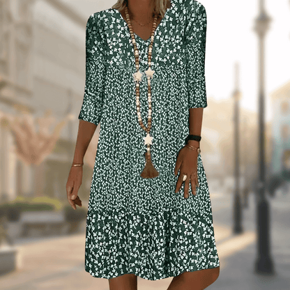 Grünes Sommerkleid mit weißem Blumenmuster, Dreiviertelärmel, V-Ausschnitt und langen Halsketten. Perfekt für lässige Sommermode.