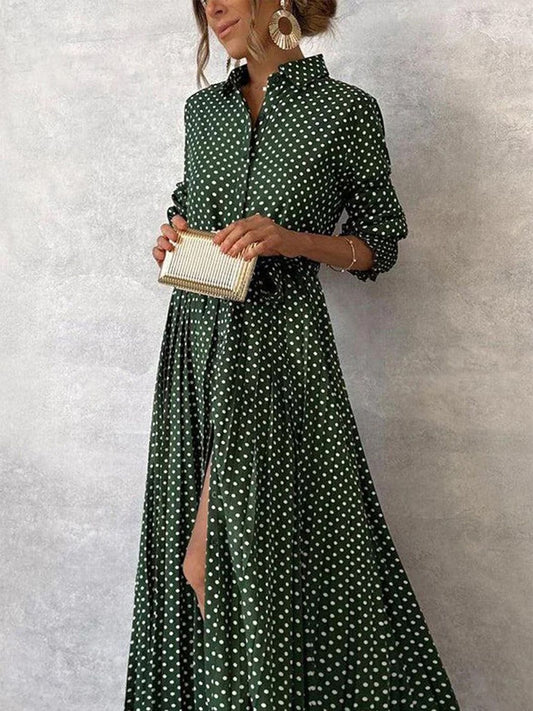 Frau in grünem gepunktetem Maxikleid mit Gürtel, hält eine goldene Clutch. Elegantes Outfit, modische Ohrringe, stilvolle Abendmode.