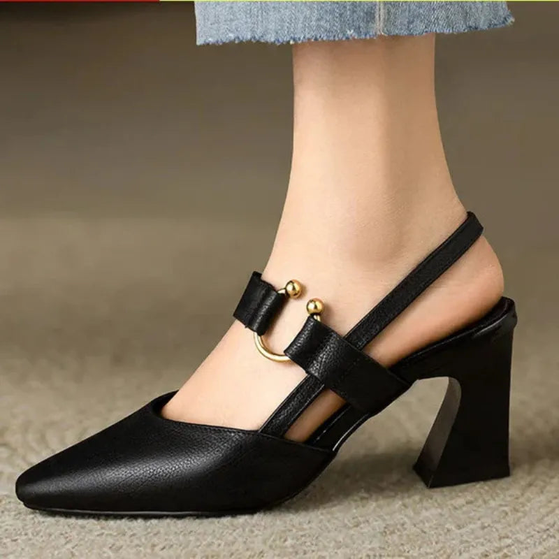 Schwarzer Damenpumps mit Blockabsatz und goldenen Verzierungen, elegantes Design, ideal für modische Anlässe, getragen mit blauer Jeans.