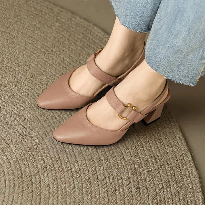 Beige Damenpumps mit Blockabsatz und Riemen, getragen auf einem runden Teppich. Modische Schuhe für elegantes Outfit, ideal für Büro oder Freizeit.