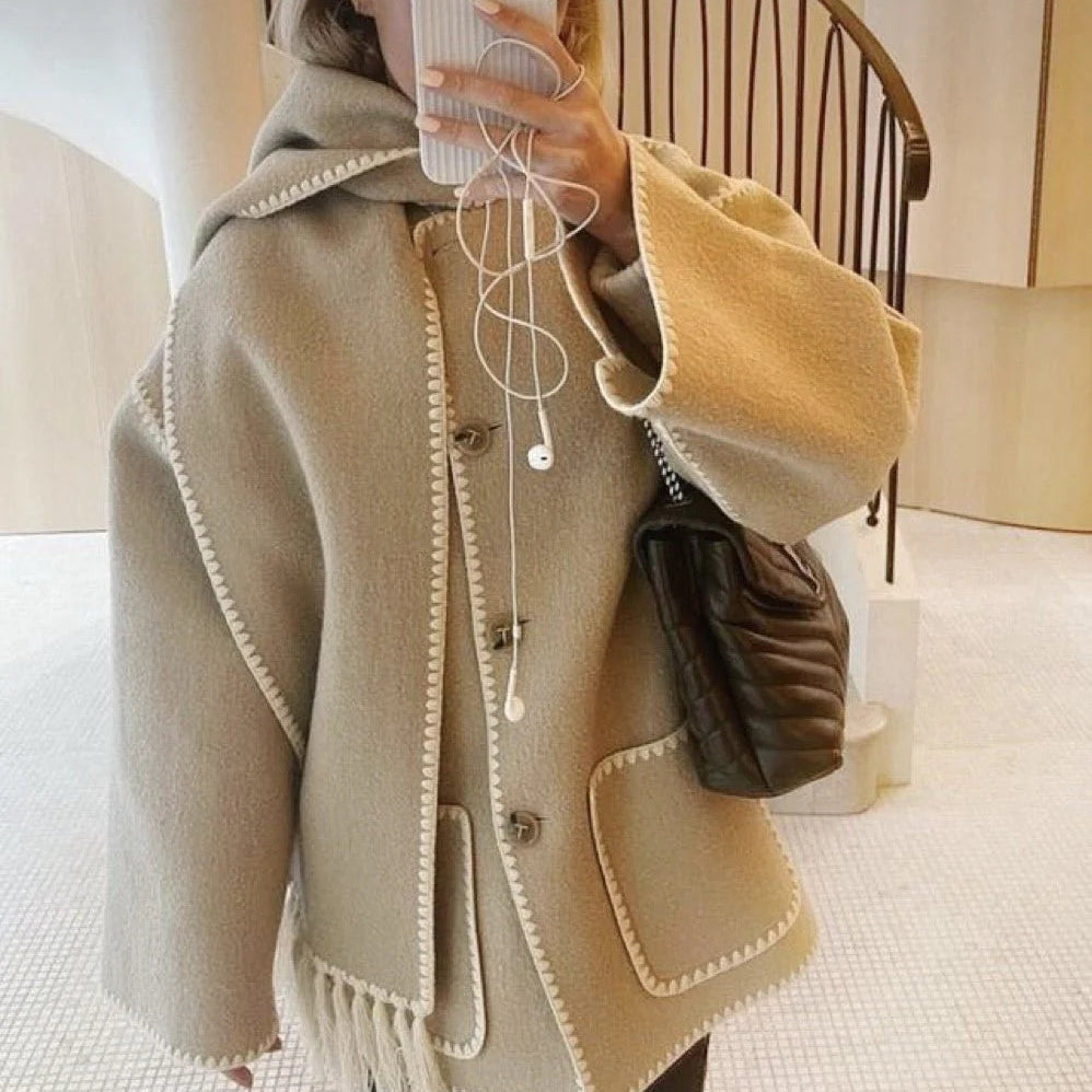 Frau in beigem Wollmantel mit Kapuze, hält Smartphone, trägt Kopfhörer und schwarze Umhängetasche. Modetrend, Herbstmode, Damenbekleidung.