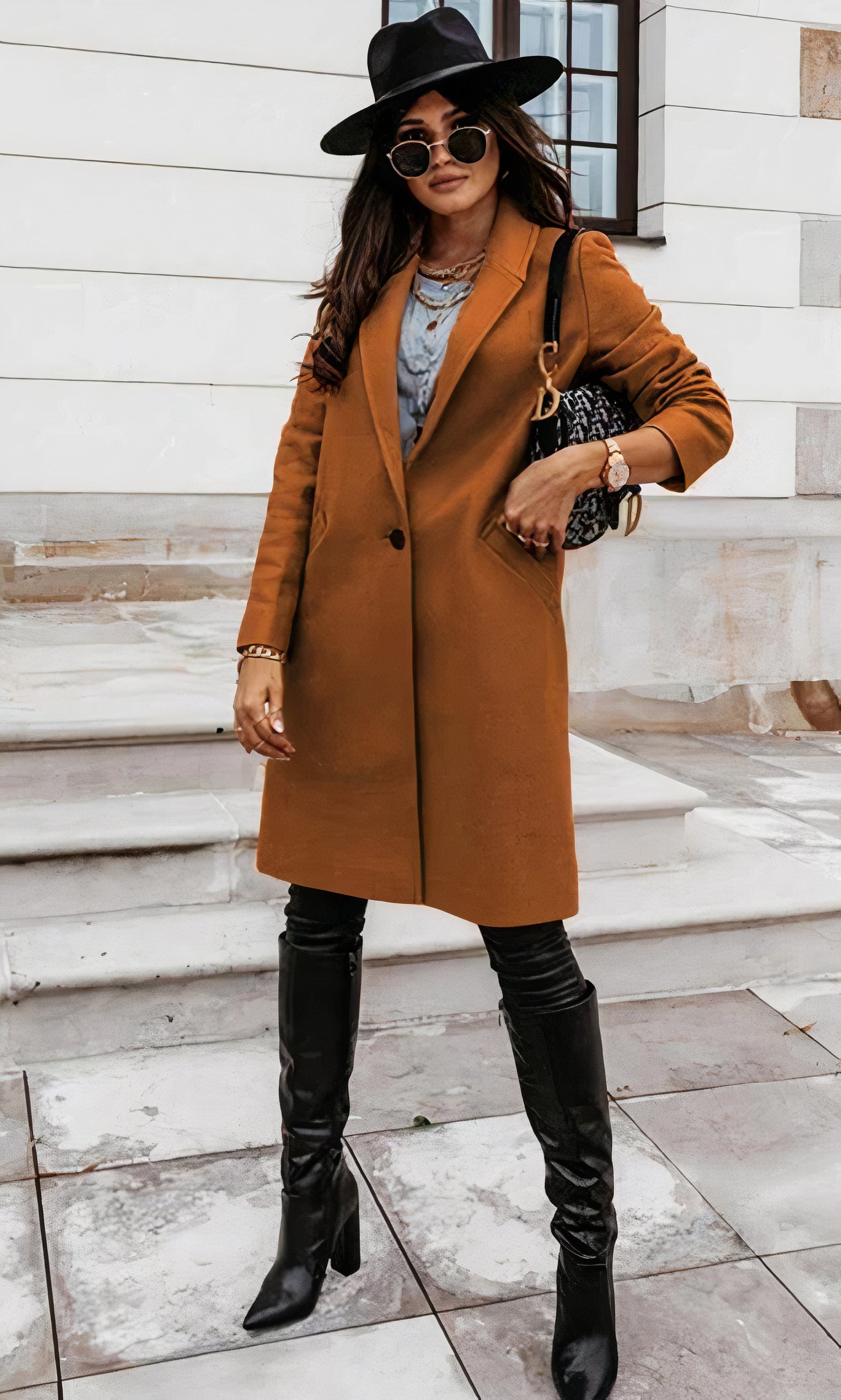 Frau in braunem Mantel, schwarzem Hut und Stiefeln auf Treppe. Modischer Herbstlook, stilvolle Accessoires, urbane Eleganz.