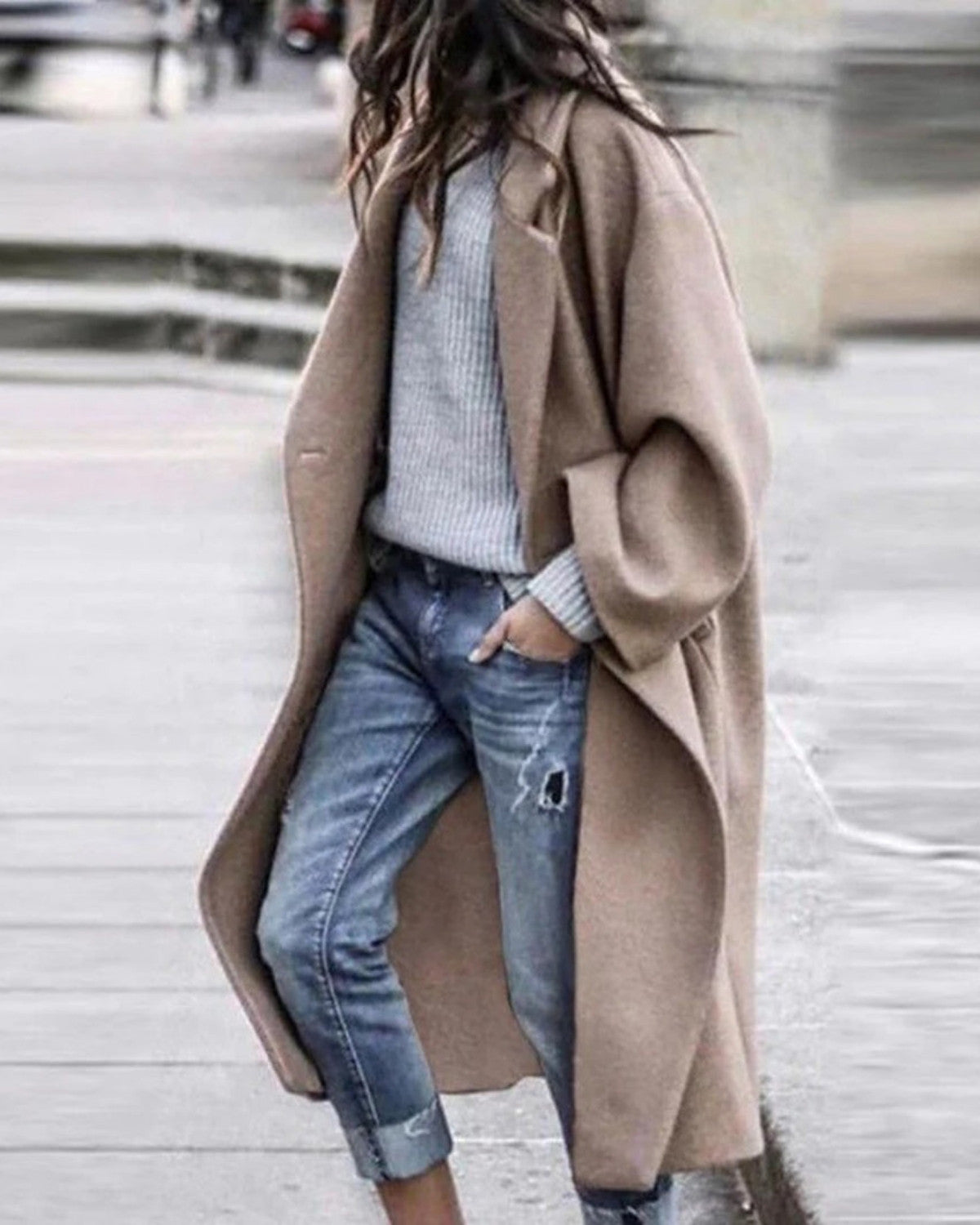Frau in beigem Wollmantel, grauem Pullover und zerrissenen Jeans auf der Straße. Modetrend, Herbstmode, lässiger Stil, urbane Kleidung.
