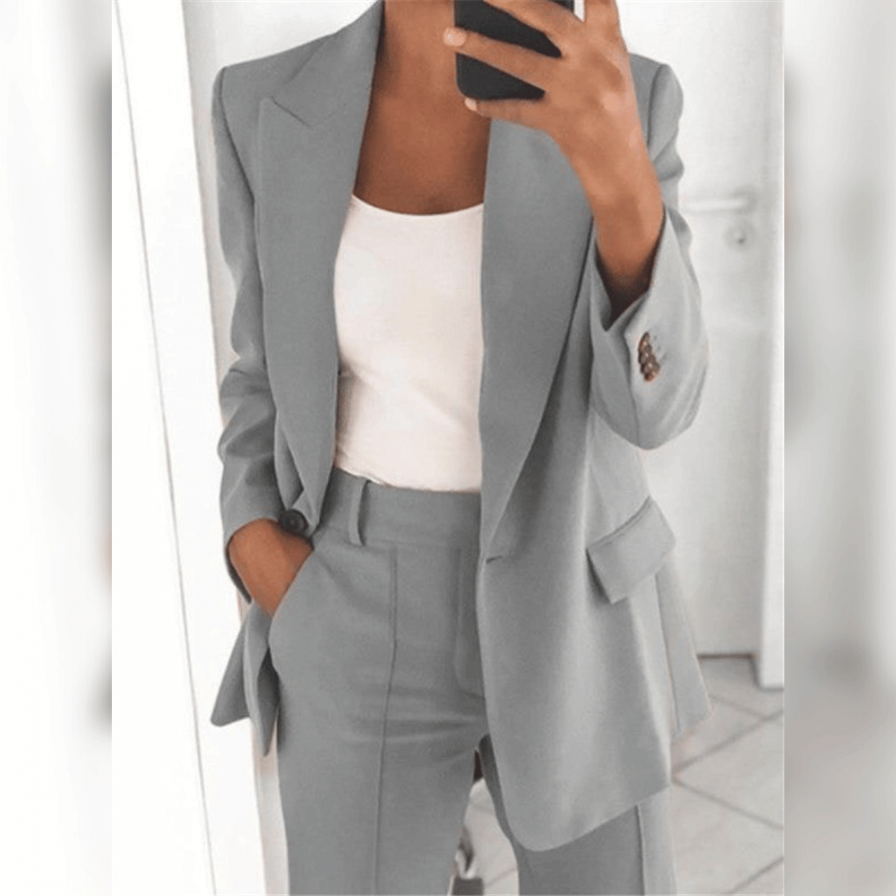 Grauer Damenanzug mit Blazer und Hose, kombiniert mit weißem Top. Businessmode, eleganter Look, moderne Damenbekleidung.