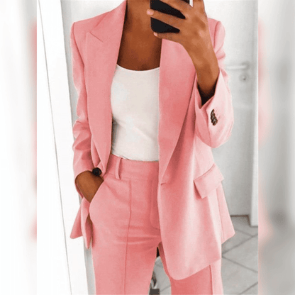 Dame in rosa Anzug mit weißem Top, hält Smartphone. Eleganter Business-Look, modische Damenbekleidung, Büro-Outfit, stilvolle Mode.