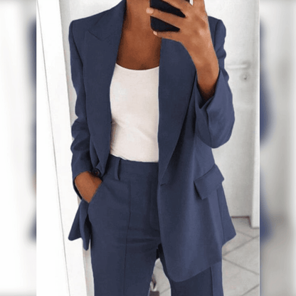 Dame im eleganten, dunkelblauen Hosenanzug mit weißem Top, hält Smartphone. Businessmode, stilvoll, modern, Büro-Outfit.
