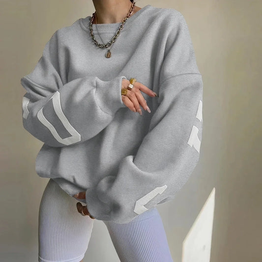 Grauer Oversize-Pullover mit weißen Streifen, kombiniert mit weißen gerippten Leggings. Modischer Look, ideal für lässige Outfits und Streetwear.