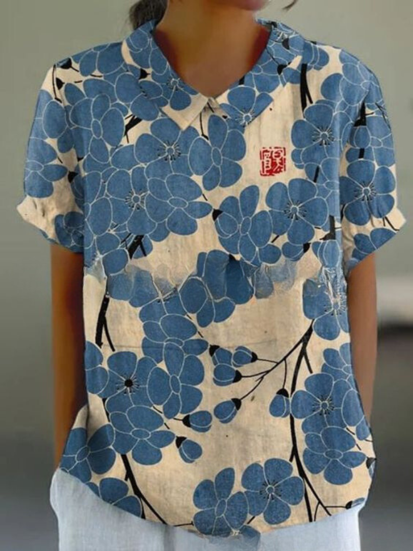 Damenbluse mit blauem Blumenmuster auf beigem Hintergrund, kurzärmelig, lässiger Stil, asiatisches Design, ideal für Sommermode.