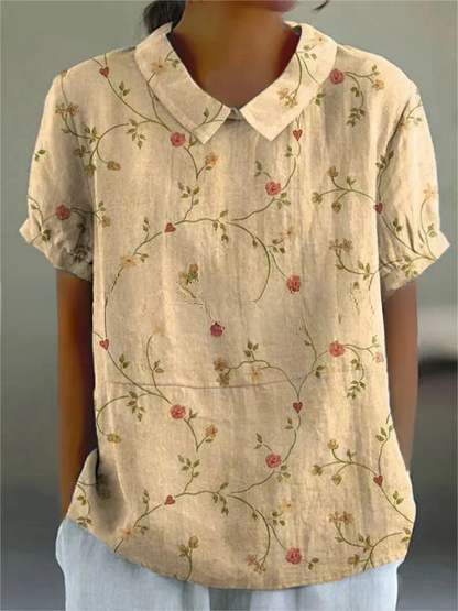 Frau trägt beige Bluse mit floralem Muster, kurzen Ärmeln und Kragen. Modetrend, Damenbekleidung, Sommeroutfit, stilvolle Bluse.