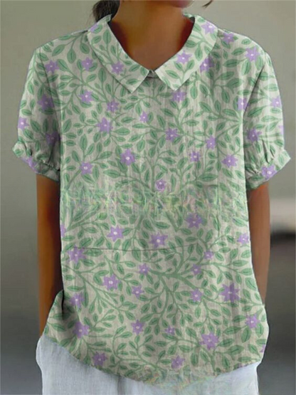 Damenbluse mit grünem Blatt- und lila Blumenmuster, kurzärmelig, klassischer Kragen, lässiger Stil, ideal für Sommermode.