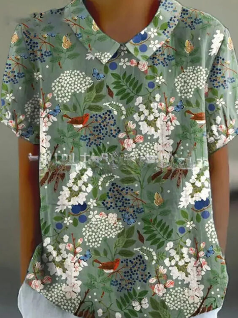 Grüne Damenbluse mit floralem Muster, Schmetterlingen und Vögeln. Kurzarm, Hemdkragen, Sommermode, stilvoll und farbenfroh.