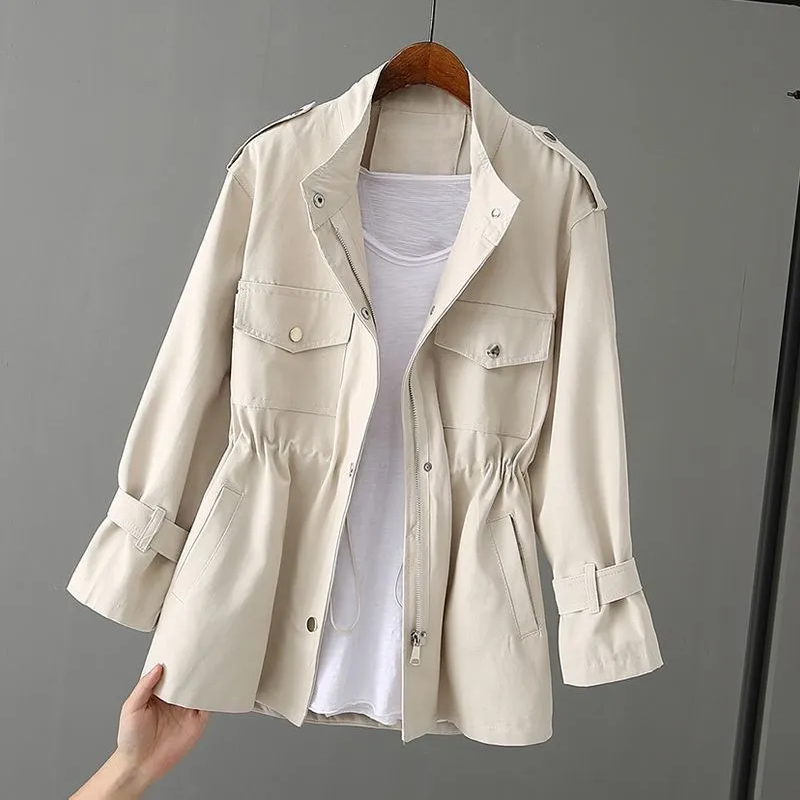 Beige Damenjacke mit Kordelzug, Reißverschluss und Taschen, über weißem T-Shirt auf Holzkleiderbügel. Modische Übergangsjacke für Frühling.