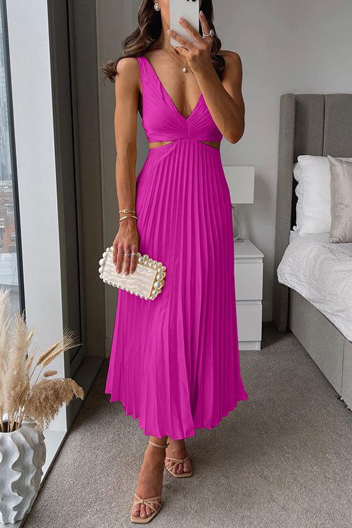 Frau in pinkem, plissiertem Kleid mit V-Ausschnitt, hält eine Perlen-Clutch, steht in modernem Schlafzimmer. Elegante Abendmode, stilvoller Look.