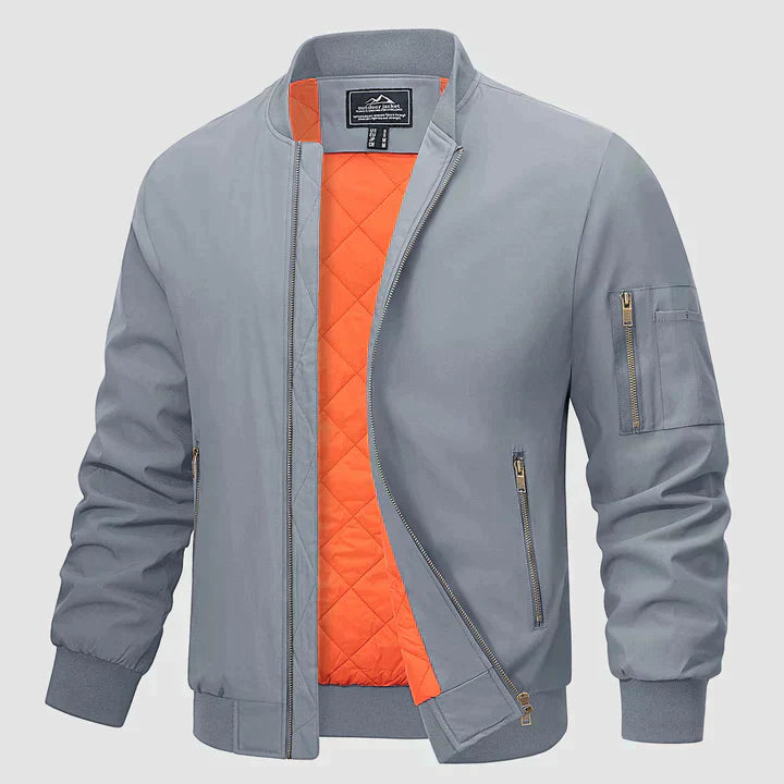 Graue Bomberjacke mit orangefarbenem Innenfutter, Reißverschlusstaschen und gerippten Bündchen. Modische Herrenjacke, ideal für Herbst und Frühling.