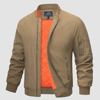 Khakifarbene Bomberjacke mit orangefarbenem Innenfutter, Reißverschlusstaschen und Ärmeltasche. Modische Herrenjacke, ideal für Herbst und Frühling.
