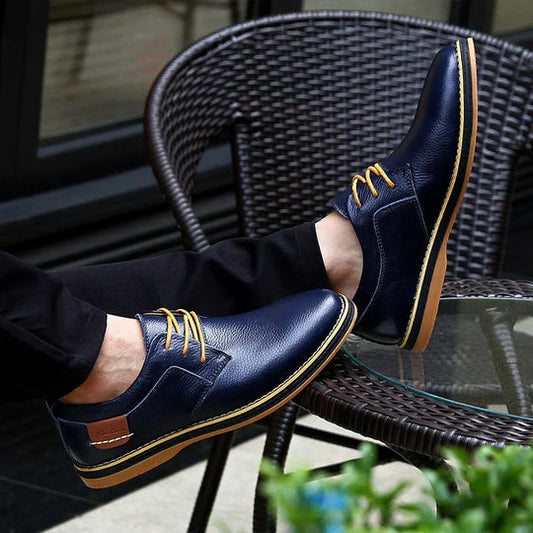 Elegante blaue Lederschuhe mit gelben Schnürsenkeln auf einem Rattanstuhl. Herrenmode, stilvolle Freizeitschuhe, modernes Schuhdesign.