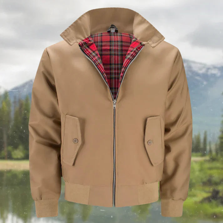 Beige Herren-Bomberjacke mit rotem Karofutter, Reißverschluss und Taschen, vor Berglandschaft. Stilvolle, warme Herrenmode für Herbst und Winter.