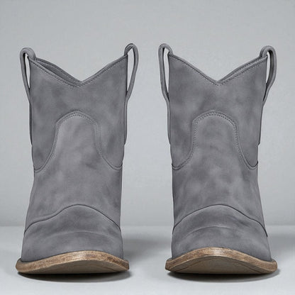 Graue Cowboystiefel aus Wildleder mit Holzsohle, Vorderansicht. Modische Westernstiefel für Damen, ideal für Herbst- und Winteroutfits.
