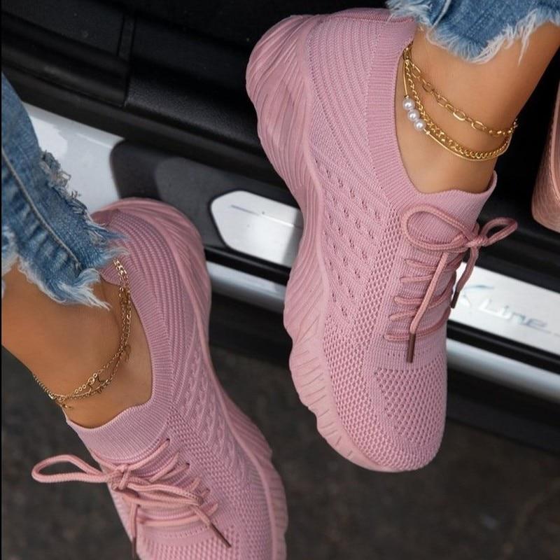 Rosa Sneaker mit dicker Sohle, getragen mit Jeans und goldenen Fußkettchen. Modische Damen-Sportschuhe, ideal für trendige Freizeitlooks.