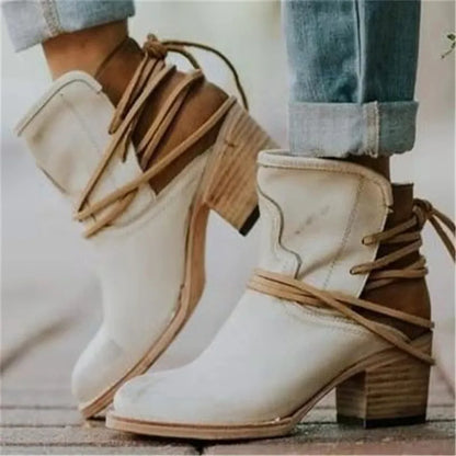 Weiße Cowboystiefel mit braunen Schnürsenkeln und Blockabsatz, getragen mit hochgekrempelten Jeans. Modische Damenstiefel, Westernstil.