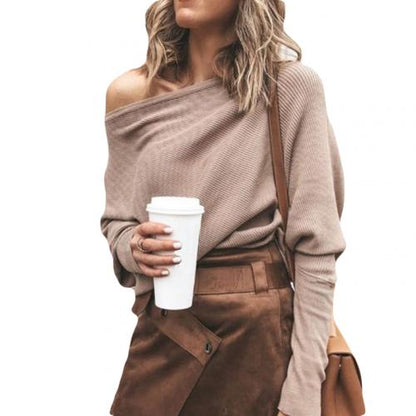Frau in beigem Off-Shoulder-Pullover und braunem Rock hält Kaffeebecher. Modetrend, Herbstoutfit, Streetstyle, Damenmode.